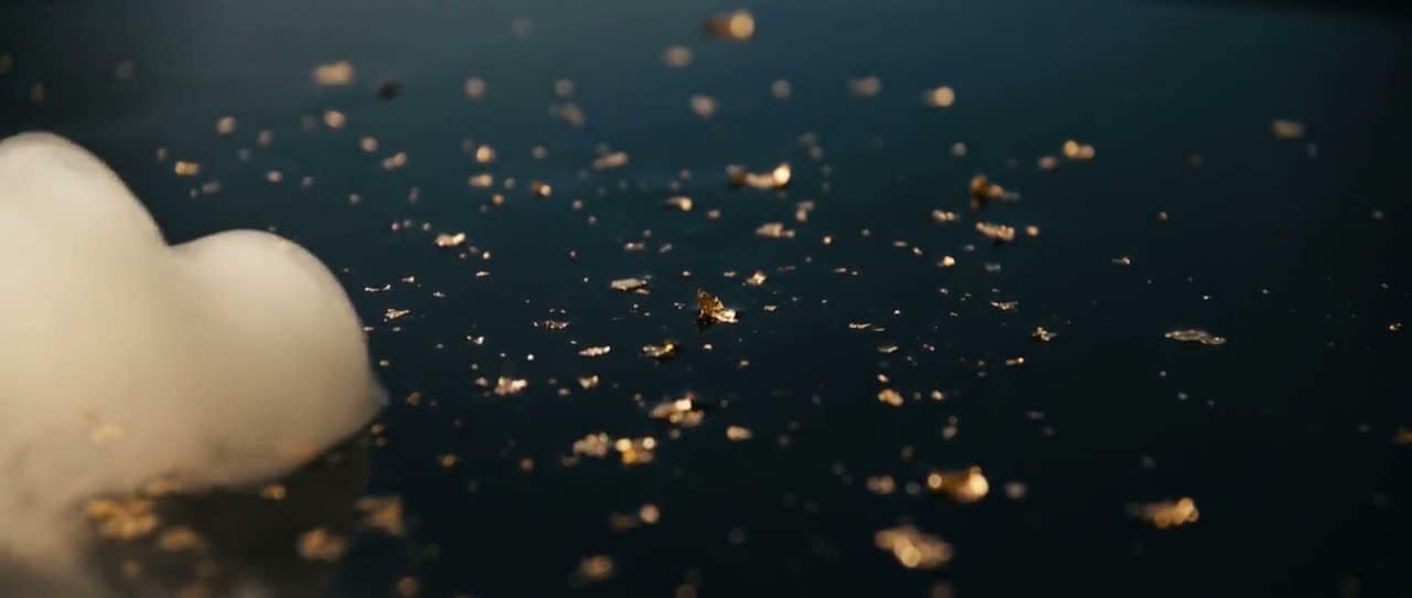 Flecks of gold leaf suspended in dark water, drifting slowly and catching the light one after another.